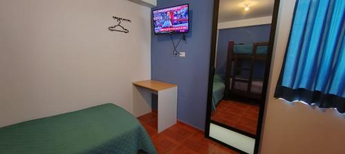 Habitación con cama, espejo y TV. en Hostal Bryan, en Tacna