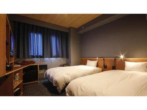 a hotel room with two beds and a flat screen tv at dogo hakuro - Vacation STAY 80202v in Matsuyama