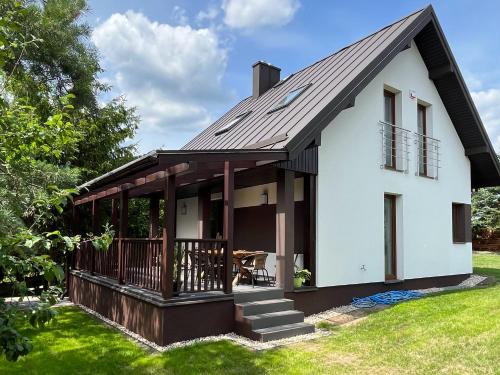 uma casa branca com um telhado preto em Modern Village em Nowinka