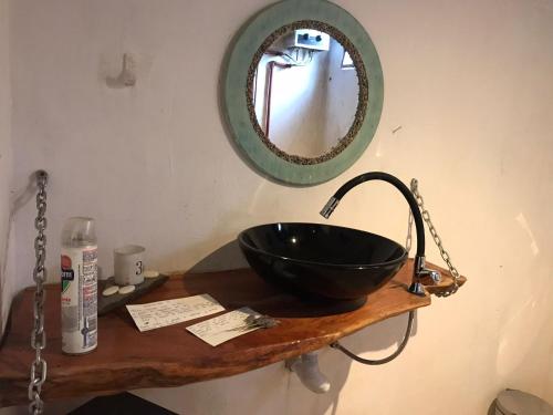 - un bol noir sur un comptoir en bois avec un miroir dans l'établissement El Albergue del Paso Polo (Quebrada de los Cuervos), à Isla Patrulla