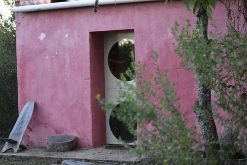 uma casa de cão rosa com uma porta e uma janela em El Albergue del Paso Polo (Quebrada de los Cuervos) em Isla Patrulla