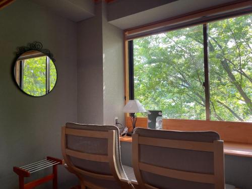 Zimmer mit einem Schreibtisch mit 2 Stühlen und einem Fenster in der Unterkunft Towadakohan Sakura - Vacation STAY 80357v in Towada