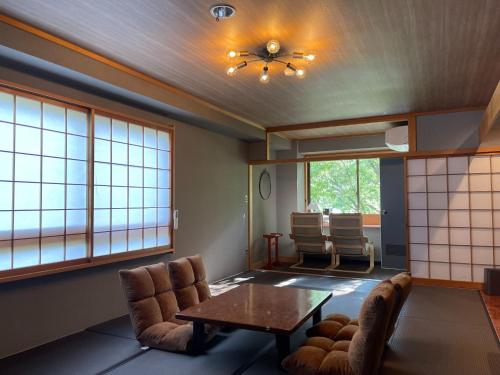 a living room with a table and chairs and windows at Towadakohan Sakura - Vacation STAY 03811v in Towada