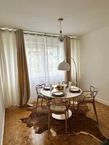 een eetkamer met een tafel en stoelen en een raam bij Appartement neuf à boulogne à 3 mins à pieds du métro in Boulogne-Billancourt