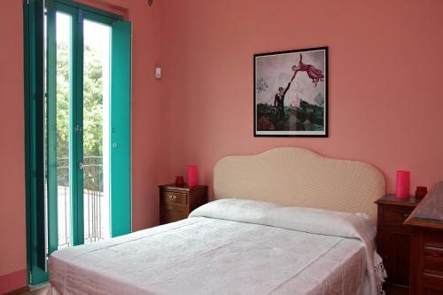 a bedroom with a bed with pink walls and a window at Agriturismo Petrara in Simeri