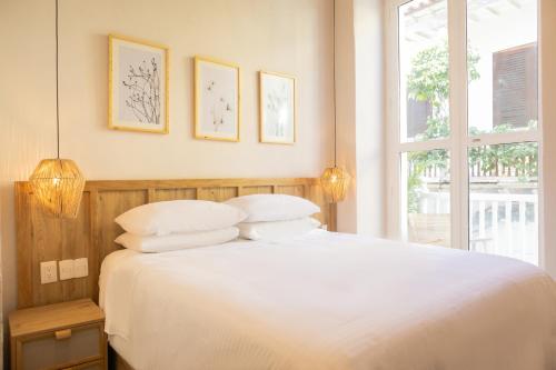 a bedroom with a white bed with two pillows and a window at Hotel Casa La Mantilla by Faranda Boutique in Cartagena de Indias
