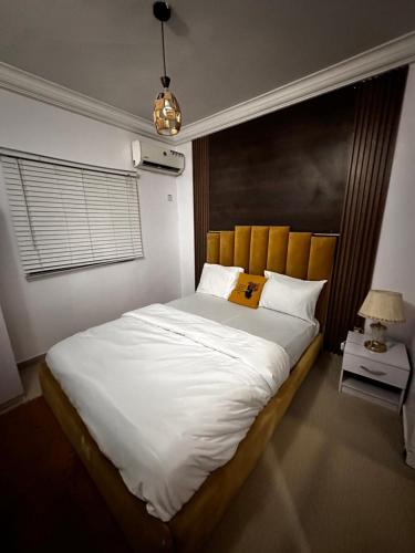 a bedroom with a large white bed with a yellow pillow at Daisies in Lekki