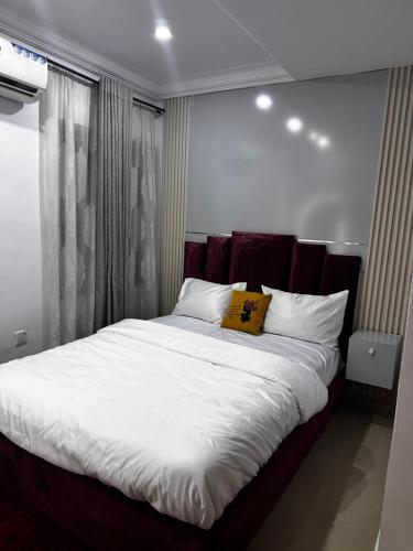 a bedroom with a large bed with white sheets and pillows at Daisies in Lekki