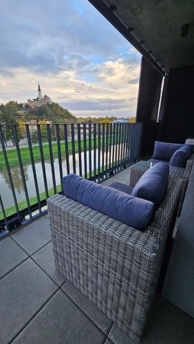 balcón con almohadas azules y vistas al agua en Apartmán PROMENÁDA en Nitra