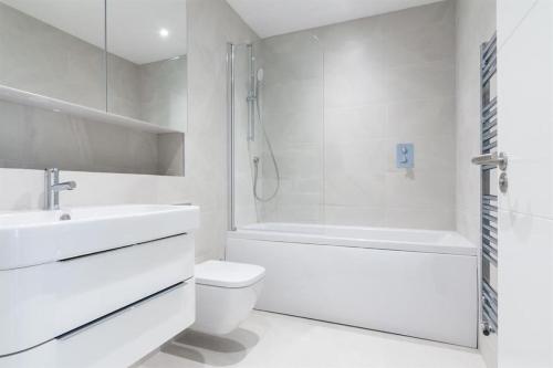 ein weißes Badezimmer mit einer Badewanne, einem WC und einem Waschbecken in der Unterkunft Farringdon Apartments in London