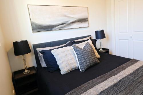 a bedroom with a bed with pillows and two lamps at Central 3 Queen Beds,Double Garage,Disney+ in Edmonton