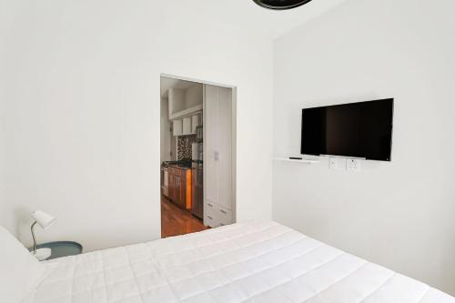 um quarto branco com uma cama e uma televisão de ecrã plano em Apartment 799: Hells Kitchen em Nova York