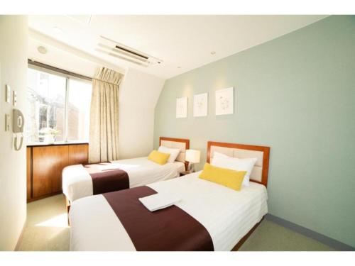 2 camas en una habitación pequeña con ventana en Tabata Oji Hotel - Vacation STAY 89843v, en Tokio