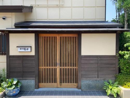 ein Gebäude mit einer Holztür mit einem Schild darauf in der Unterkunft Ryokankasuga - Vacation STAY 90832v in Nabari