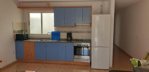 a kitchen with blue cabinets and a white refrigerator at Ático carrizal in Carrizal
