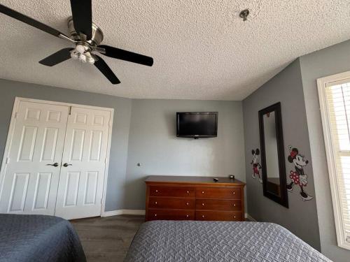 a bedroom with a ceiling fan and a bed and a dresser at Apartment very Close to Disney! in Orlando