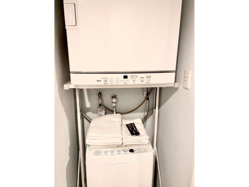 eine Küche mit einer Mikrowelle, einer Waschmaschine und einem Trockner in der Unterkunft HOTEL SANDRIVER ISHIGAKIJIMA - Vacation STAY 91454v in Ishigaki-jima