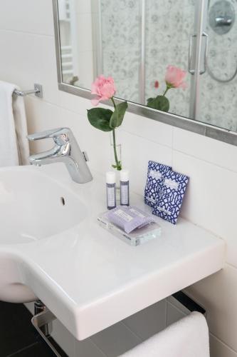 a white bathroom sink with a vase of flowers on it at Hotel La Villetta in Calenzano