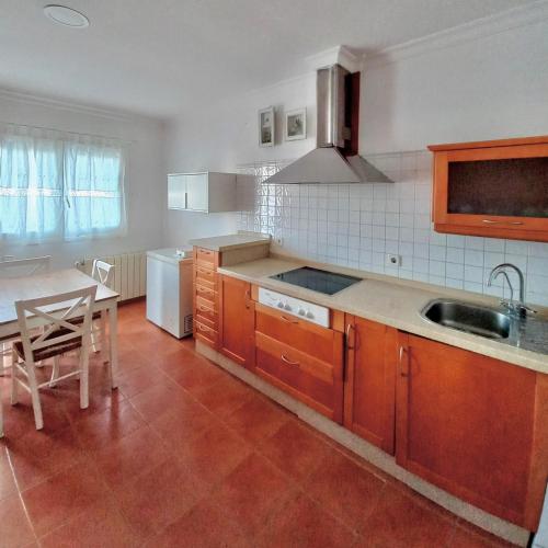 a kitchen with wooden cabinets and a table and a sink at Ático playa Barbate A 10min Zahara de los Atunes Caños de Meca Vejer de la Frontera in Barbate