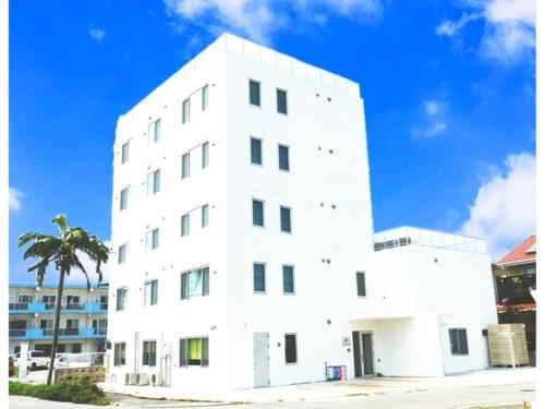 石垣島的住宿－HOTEL SANDRIVER ISHIGAKIJIMA - Vacation STAY 91470v，一座白色的建筑,前面有棕榈树
