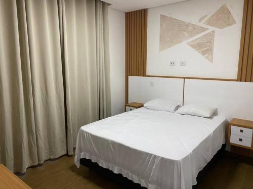 a bedroom with a white bed and a window at Linda casa em condomínio in Tatuí