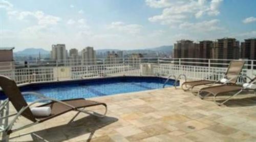 uma varanda com duas cadeiras e uma piscina num edifício em Maximus Luxury in Perdizes - Allianz - Flat at the Hotel em São Paulo