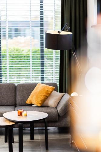 a living room with a couch and a table at Wellness bungalow with Sauna in Ermelo
