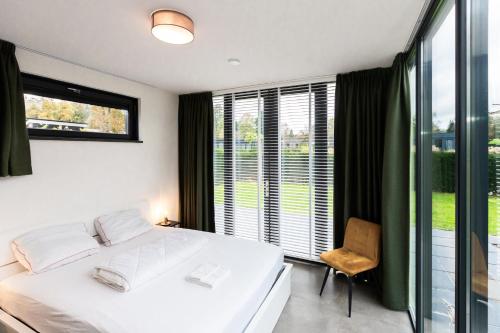 a bedroom with a white bed and a window at Wellness bungalow with Sauna in Ermelo