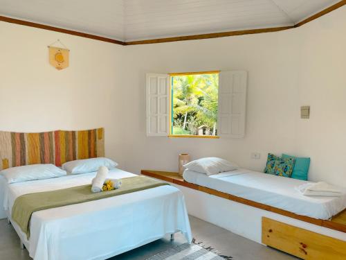 um quarto com 2 camas e uma janela em Canto do Mar - Chalés com vista pro Mar - Cumuruxatiba em Cumuruxatiba