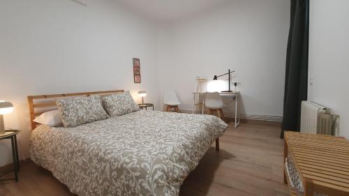a bedroom with a bed and a table and a desk at Apartamento nuevo en Terrassa Centro in Terrassa