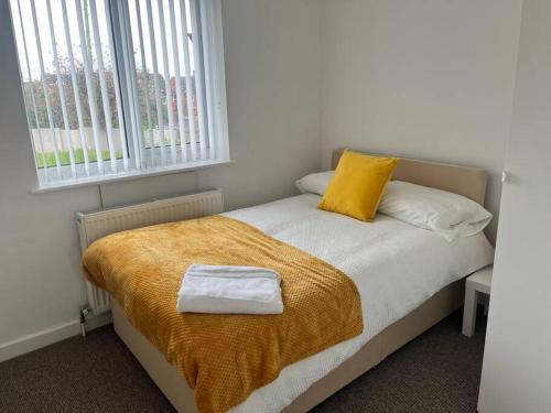 a bedroom with a bed with a yellow blanket and a window at Impressive Large 6 Bed House FREE WI FI in Lincolnshire