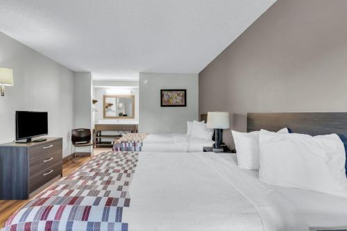 a hotel room with two beds and a television at Red Roof Inn MacClenny in Macclenny