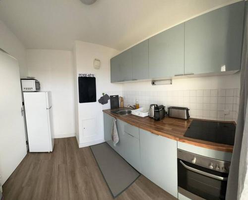 La cuisine est équipée de placards blancs et d'un réfrigérateur blanc. dans l'établissement IMEPA Appart 47m2/ Beau 2 pièces, à Rouen