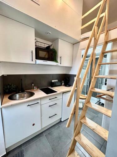 - une cuisine avec des placards blancs et une échelle dans l'établissement N3 Le Colvert - La Maison Sévigné Appart Hôtel, à Béthune
