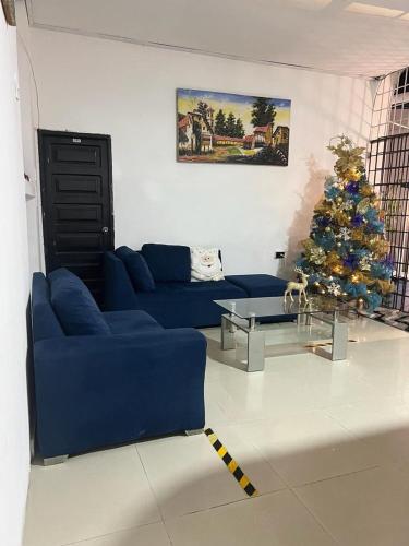a living room with a blue couch and a christmas tree at HOTEL SANTA MONICA in Barranquilla
