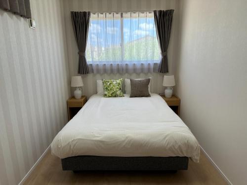 1 dormitorio con 1 cama con 2 lámparas y una ventana en Bears Stay Kumejima Villa - Vacation STAY 01033v en Kumejima