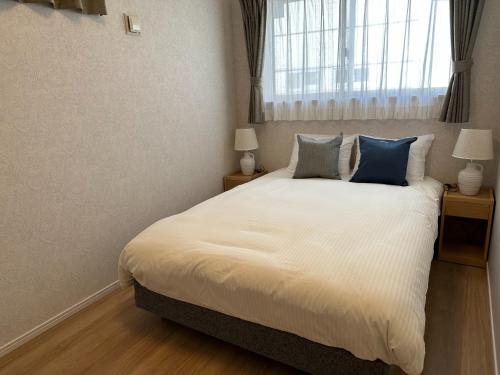 a bedroom with a white bed with blue pillows at Bears Stay Kumejima Villa - Vacation STAY 00998v in Kumejima