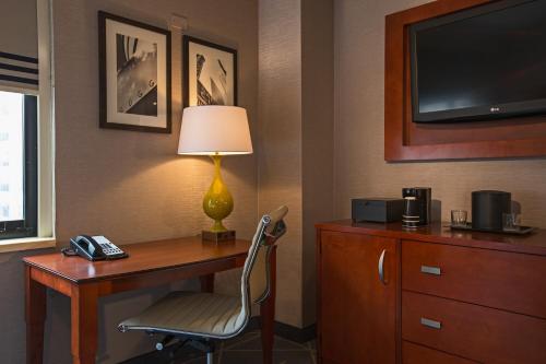 a hotel room with a desk with a lamp and a television at Courtyard by Marriott New York Manhattan/ Fifth Avenue in New York