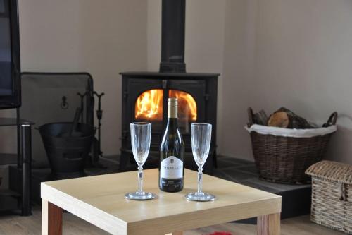a bottle of wine and two glasses on a table with a fireplace at Swallows Haven in Moneyreagh