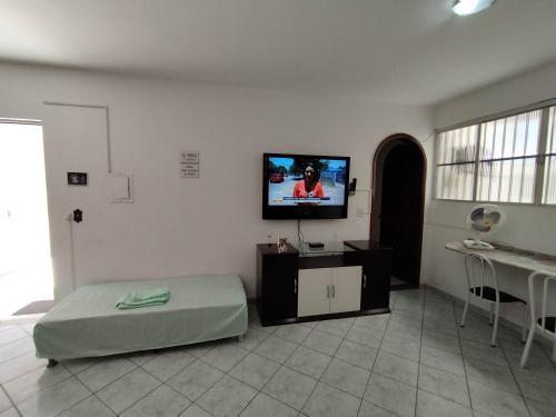 uma sala de estar com uma cama e uma televisão de ecrã plano em Seu Apto na Praia da Costa 7 Completo 2Q 2B 2S Ar Cond Geladeira Fogao TV Maq Lavar Centro Sem escadas em Vila Velha