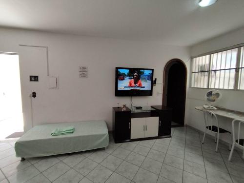 a living room with a bed and a flat screen tv at Seu Apto na Praia da Costa 7 Completo Simples e Barato 2Q Ar Cond Geladeira Fogao TV no Centro Bom para Empresas Sem escadas in Vila Velha
