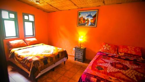 um quarto com paredes cor de laranja, uma cama e um sofá em Art & Coffee em Santa Cruz La Laguna