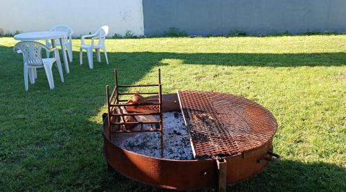 a barbecue grill in a yard with a table and chairs at El cardenal in Gualeguaychú