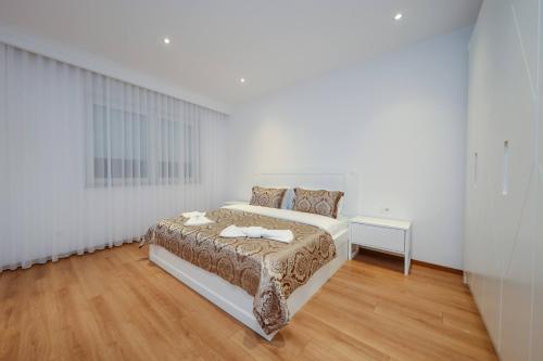 a white bedroom with a bed and a table at Hotel Apartments Ardi & Lala in Peje
