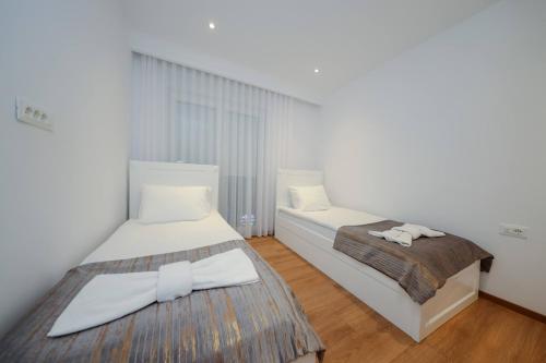 Habitación con 2 camas, paredes blancas y suelo de madera. en Hotel Apartments Ardi & Lala, en Peje