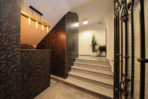 a hallway with stairs and a wall with black tiles at Hotel Apartments Ardi & Lala in Peje