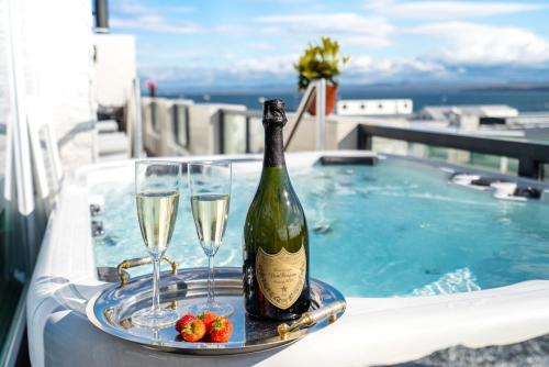 a bottle of wine and glasses on a tray next to a swimming pool at Diamond Suites by Reykjavik Keflavik Airport in Keflavík