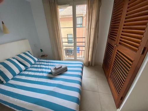 Schlafzimmer mit einem blauen und weißen Bett und einem Fenster in der Unterkunft Appartement climatisé 50m2 centre du village in Porquerolles