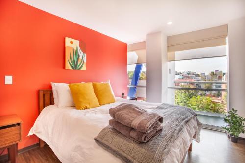 Un dormitorio con una pared de acento naranja y una cama en Moderno Mexicano 3BR/2BA 200Mbps en Ciudad de México