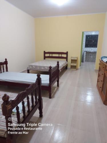 um quarto com 2 camas e uma cómoda em Pousada e Restaurante Frente ao Mar em Cananeia